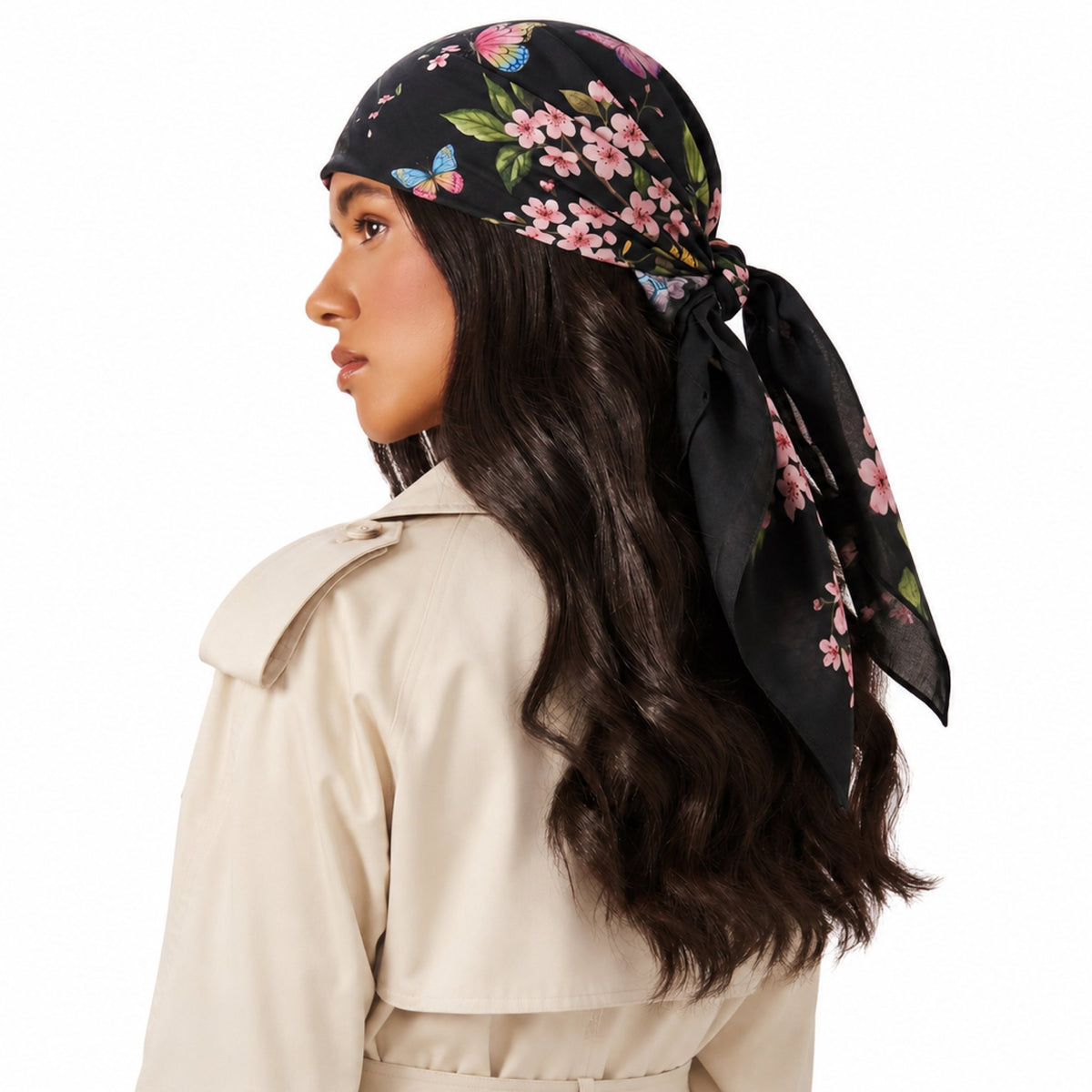 Model wearing TUK After Bloom Head Scarf in black with pink cherry blossoms and colorful butterflies, tied at the back of head.