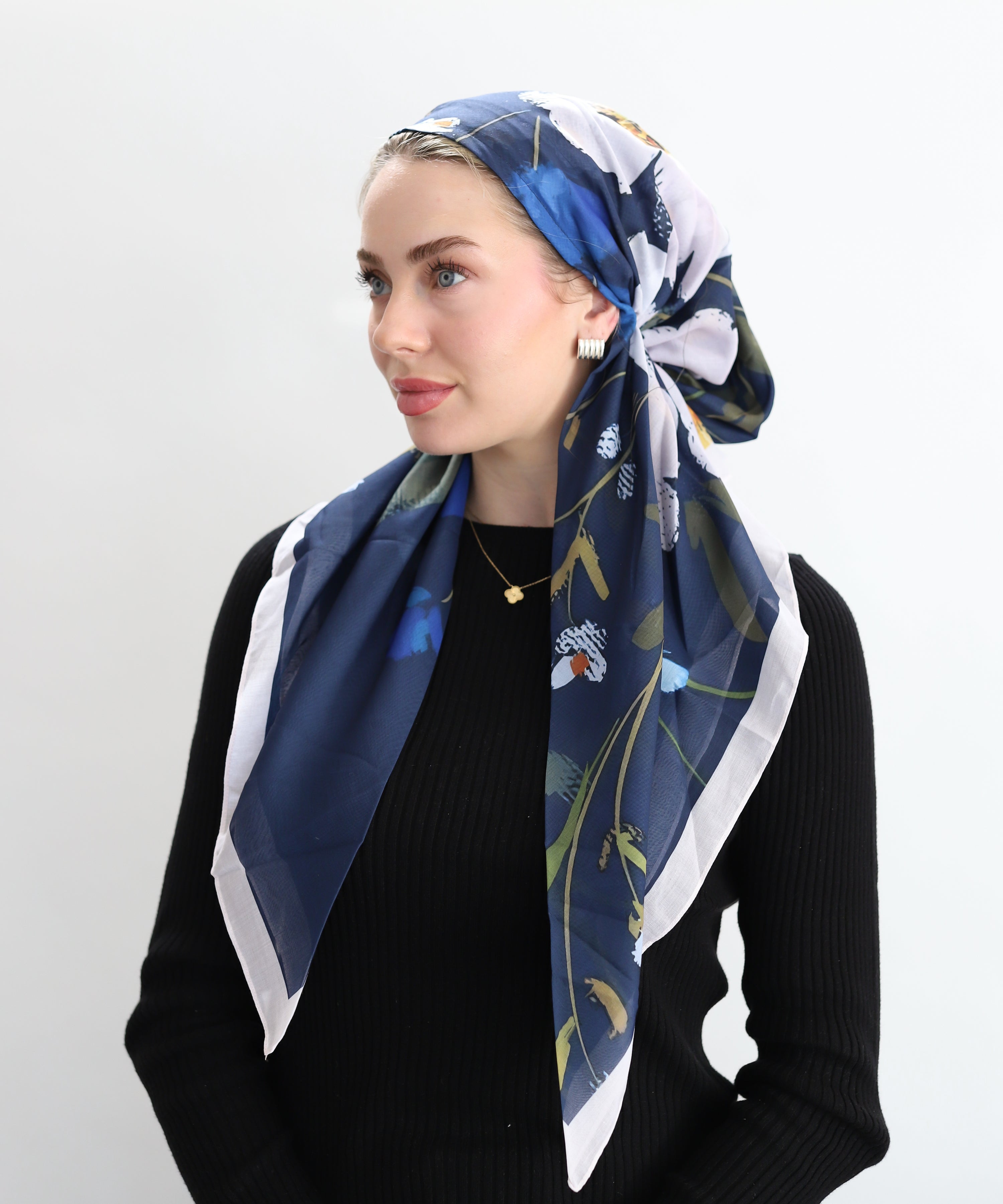 Woman wearing a TUK headscarf Blue Hour which features a deep navy canvas brought to life with painterly floral motifs and delicate butterflies.