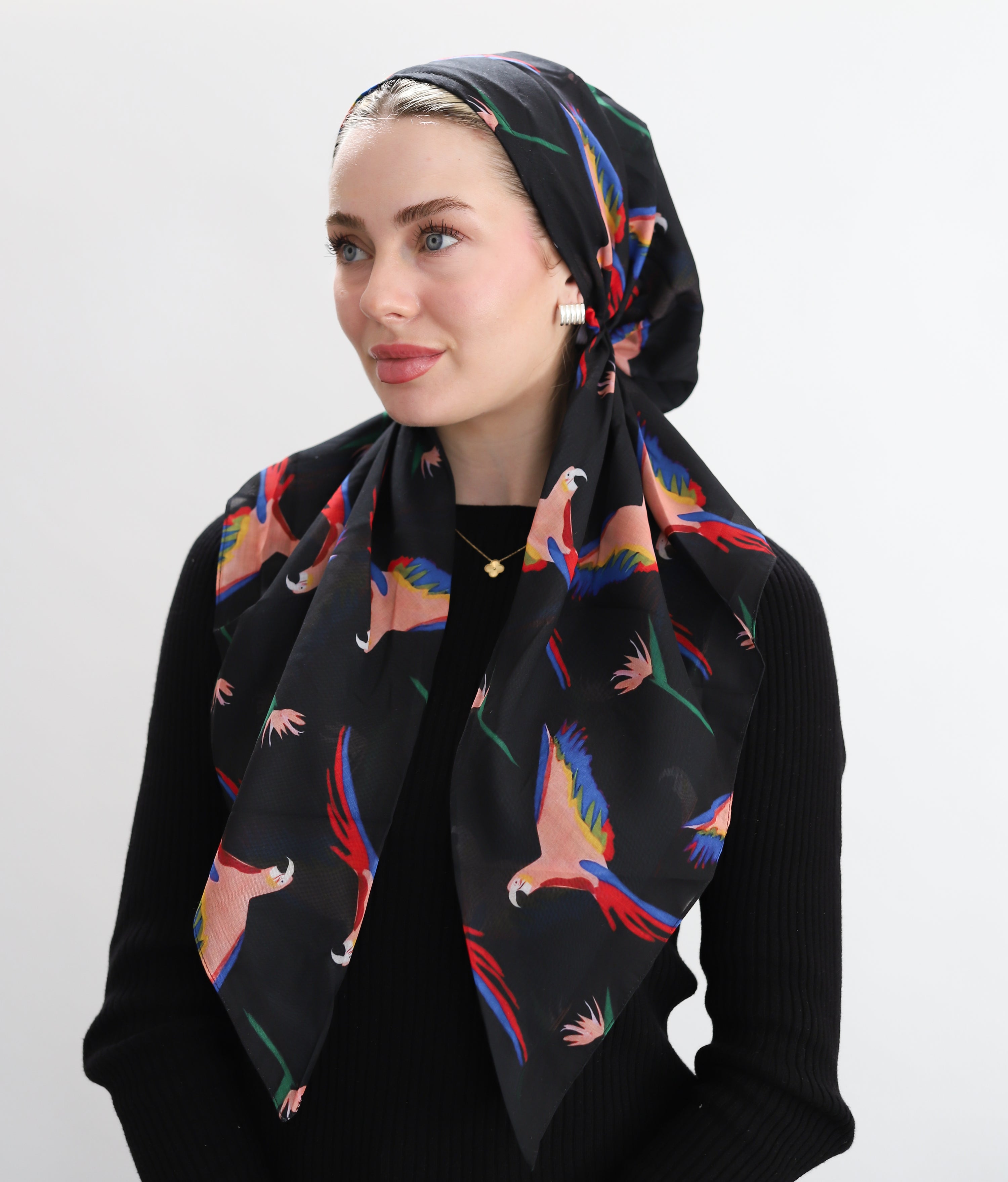 Woman wearing TUK Call Sheet which is set against Set against a deep black canvas, the design bursts to life with hand-illustrated parrots in striking hues of scarlet, cobalt, and golden peach, their wings outstretched in mid-flight.
