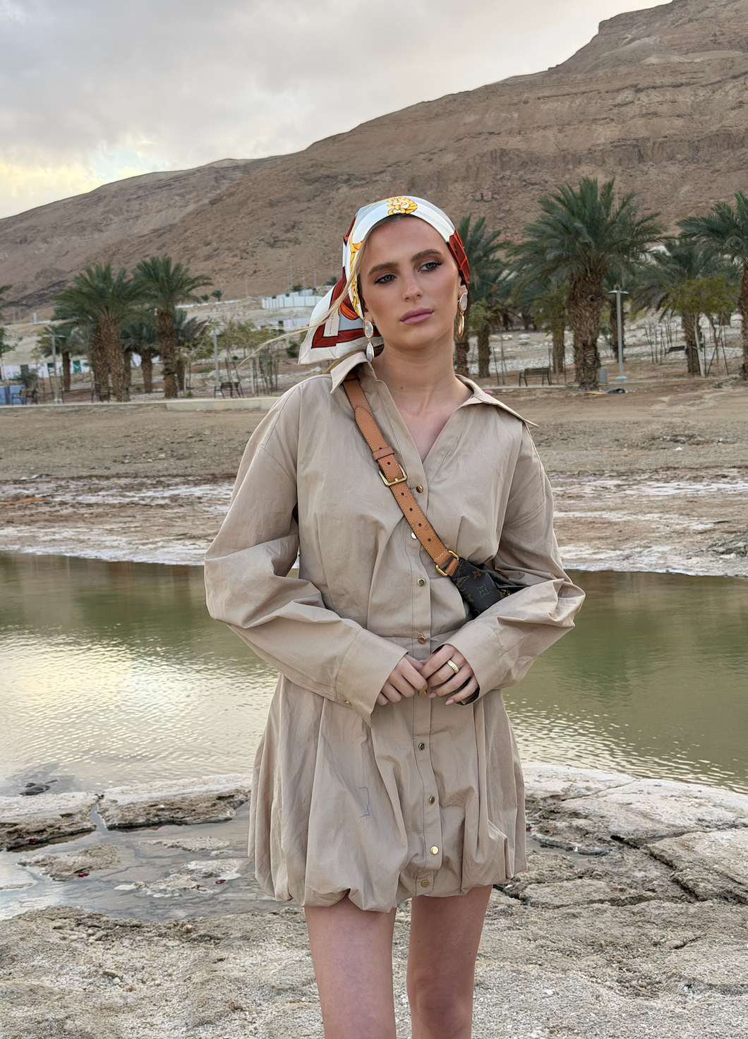 Elegant model wearing TUK Cool Reins Silk Scarf in desert oasis, styled with neutral dress and luxury crossbody bag.