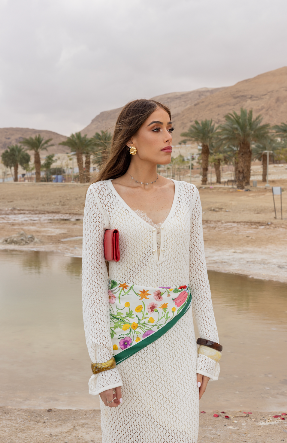 Woman wearing TUK Field Day Silk Scarf styled as a waist accessory, featuring a vibrant floral print in a desert landscape setting.