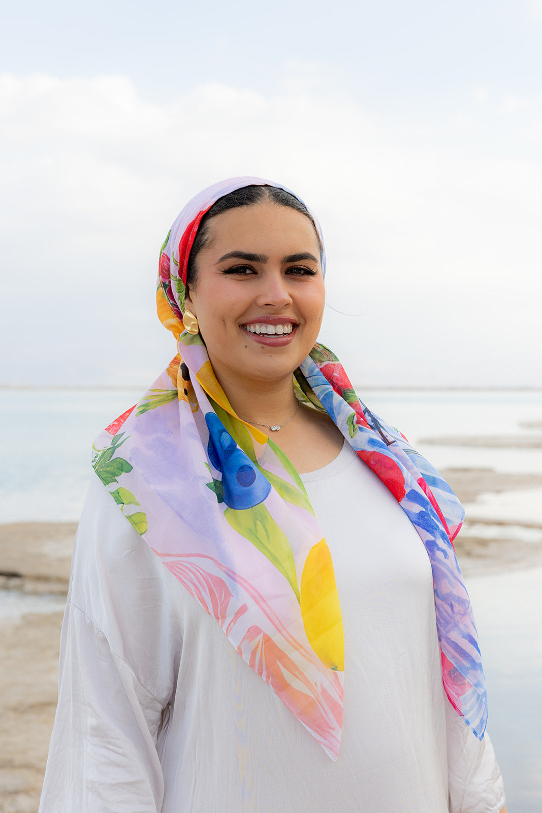Fleurs & Citrons Head Scarf by TUK featuring vibrant floral and citrus prints on a lightweight scarf styled by the sea.