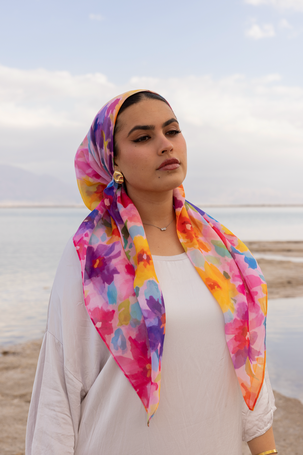TUK Love Muted Head Scarf in soft floral tones, styled elegantly by a woman by the seaside with a modern, minimal outfit.