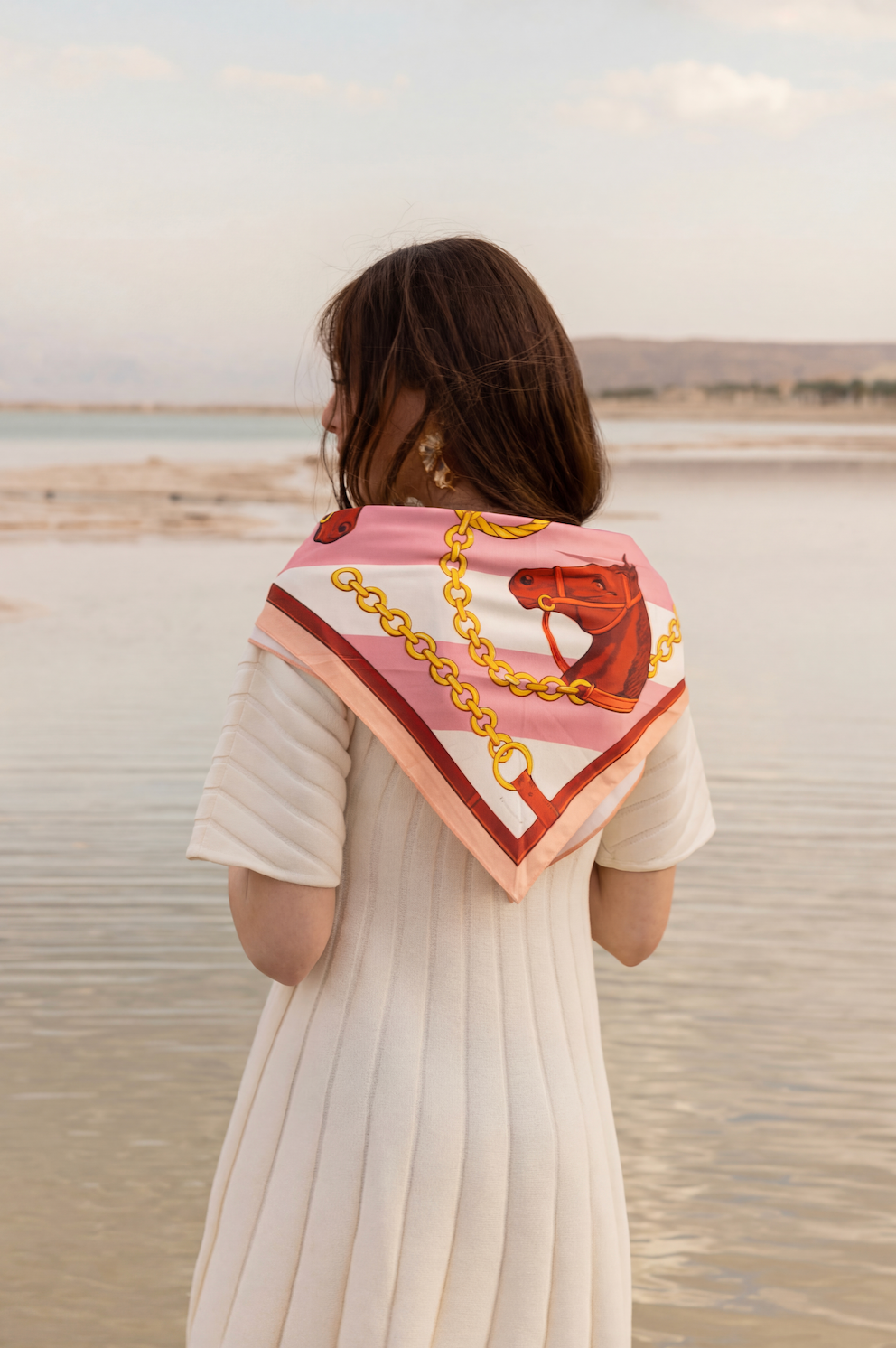 Woman wearing a patterned scarf over her shoulders with a scenic background.