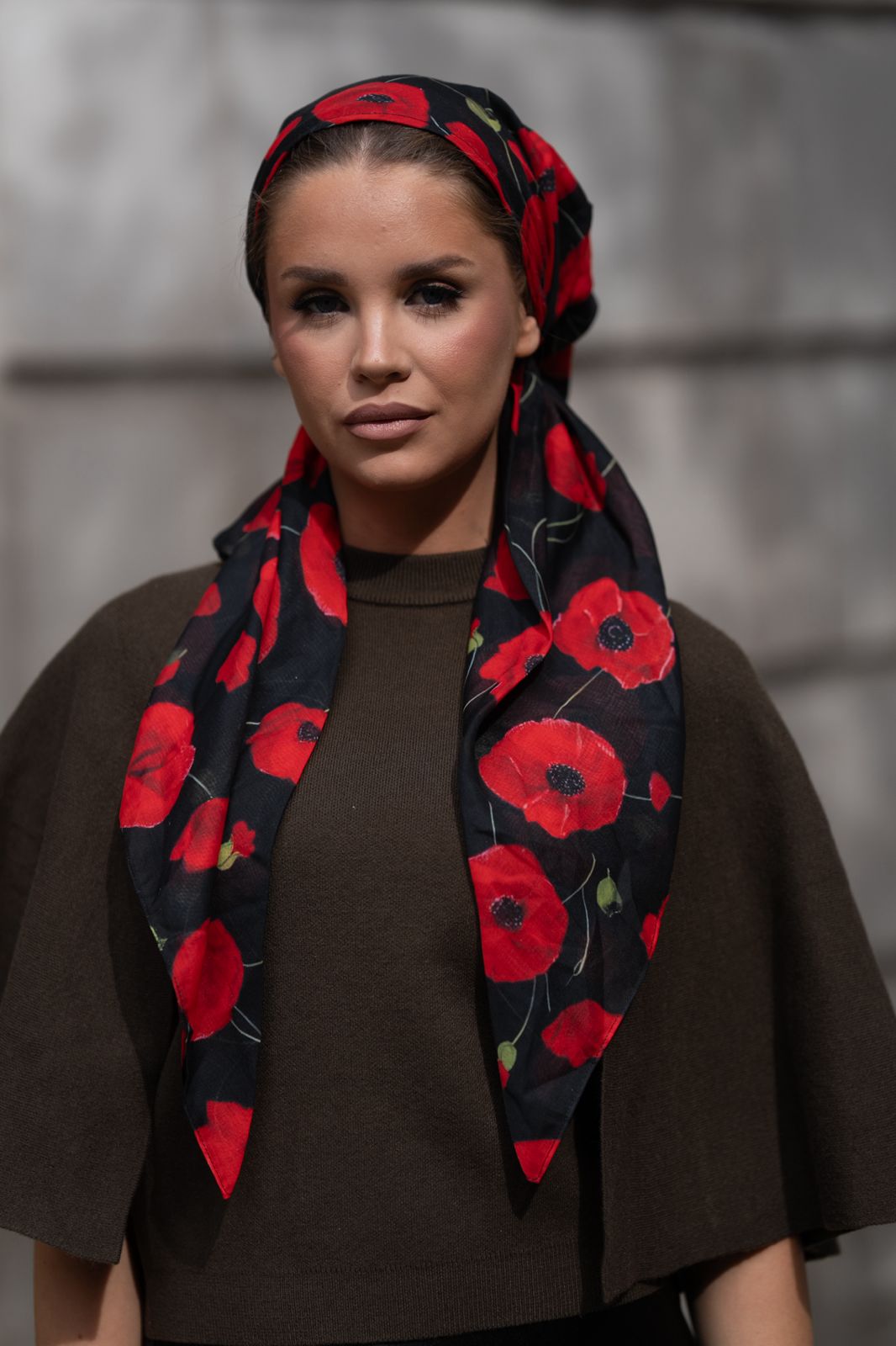 Woman wearing TUK Knockout Headscarf with bright red florals on a crisp black base make it bold, beautiful, and incredibly easy to style.