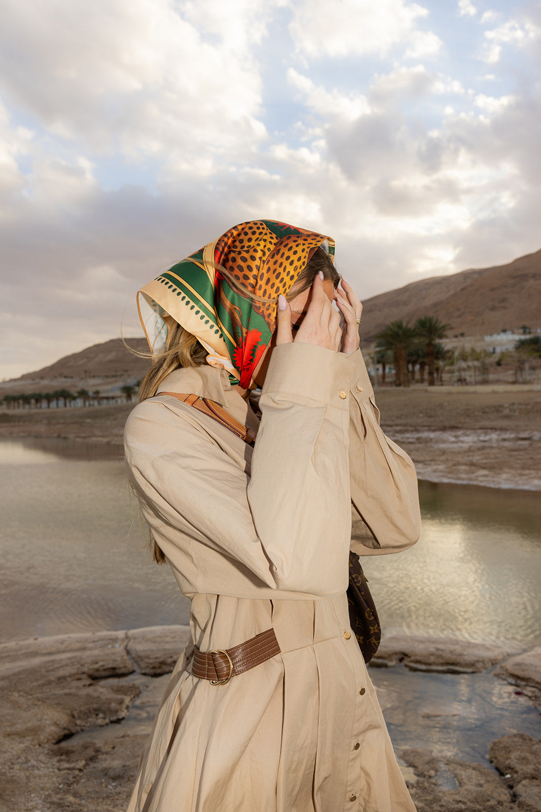 TUK Knot So Tame Silk Bandana in a bold safari print worn as a headscarf, bringing elegant style to a desert landscape.