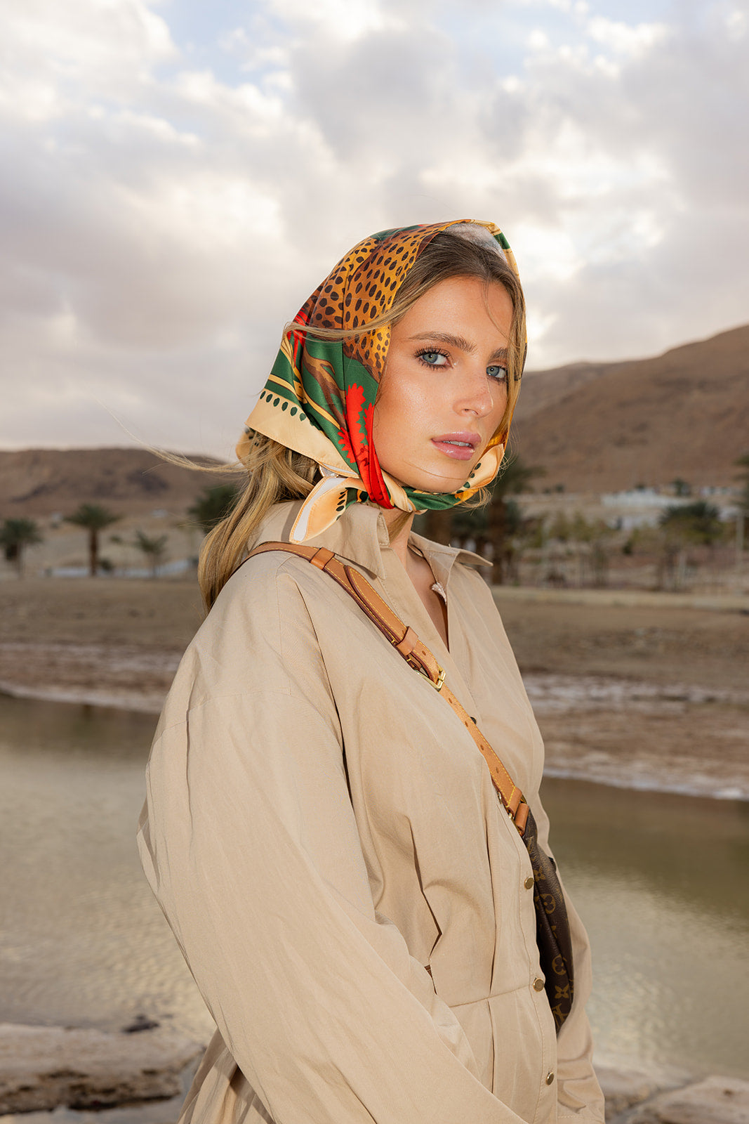 TUK Knot So Tame Silk Bandana with bold safari print styled as a headscarf, elevating a chic desert-inspired fashion look.