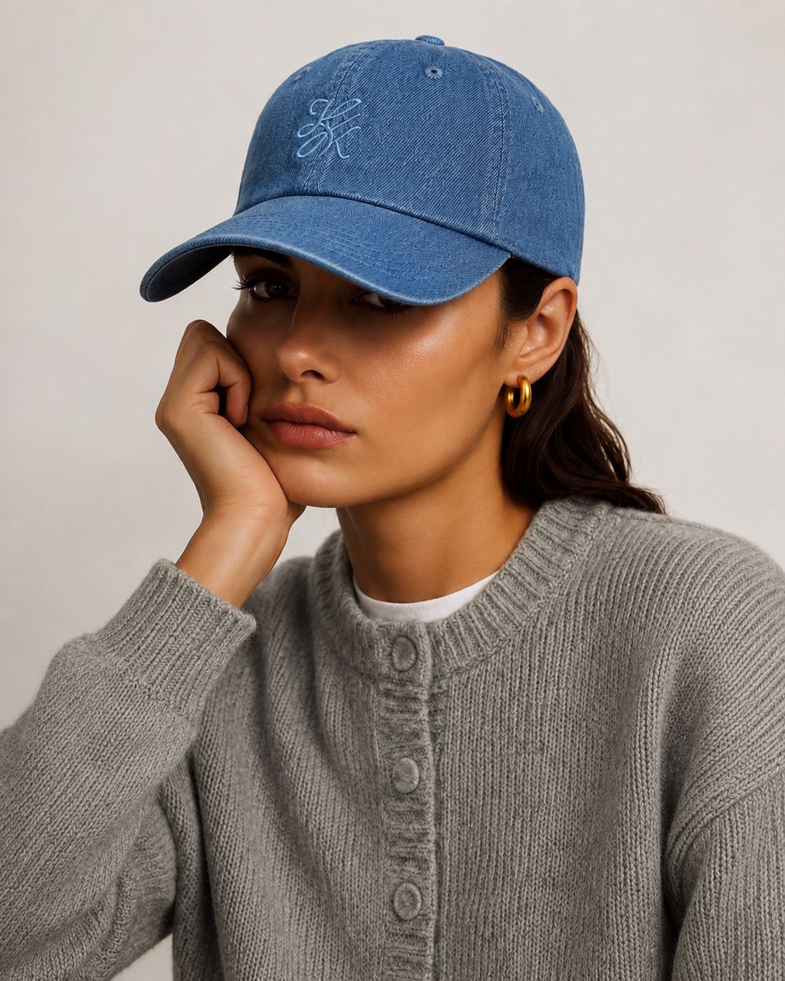Model wearing TUK Light Wash Denim Cap in soft blue washed denim with embroidered logo, adjustable baseball cap for everyday style.