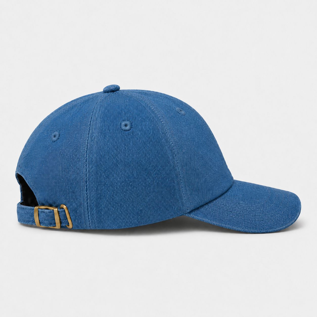 Side view of TUK Light Wash Denim Cap in soft blue washed denim with adjustable brass buckle strap and curved brim design.