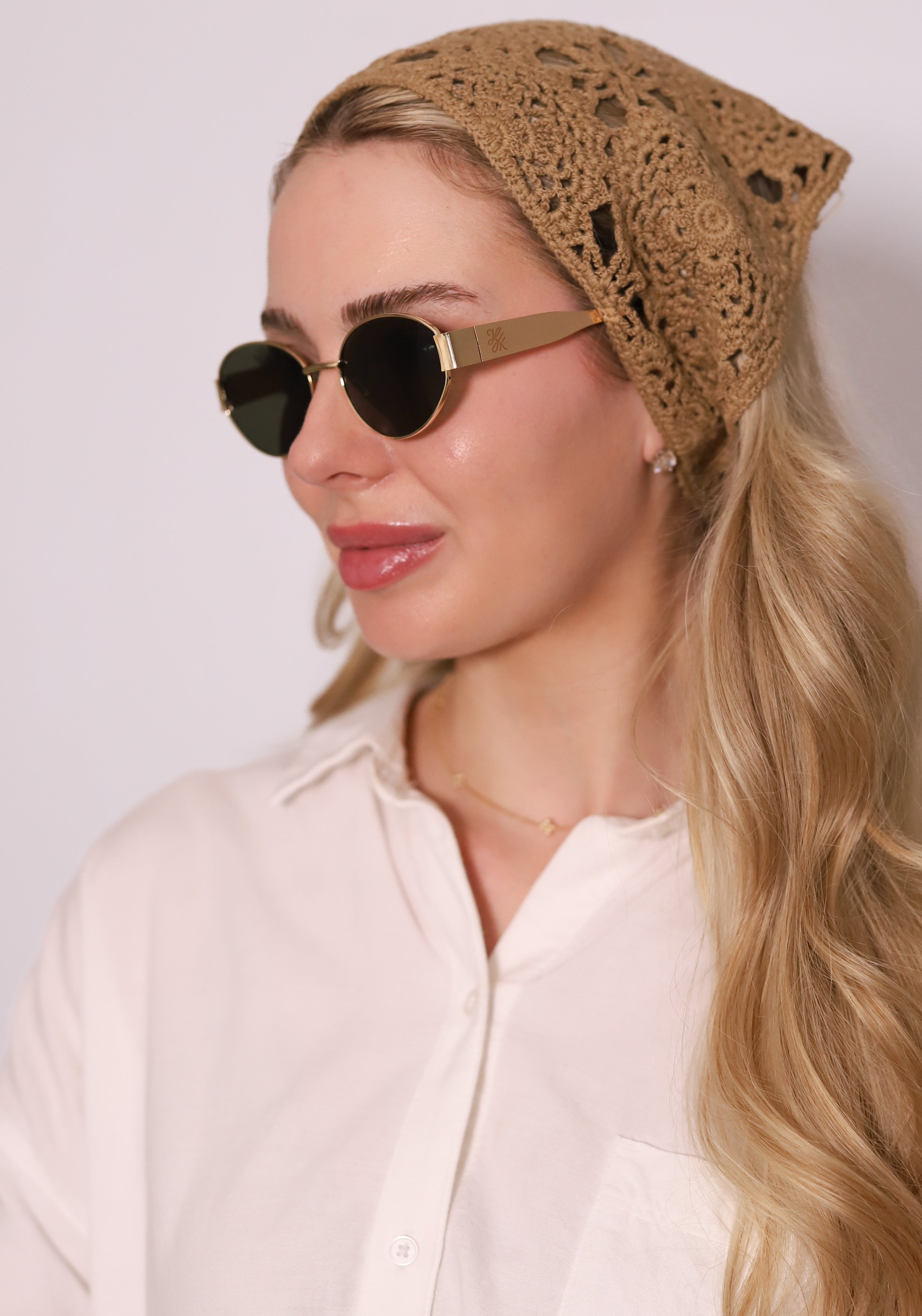 Lux Sunglasses by TUK featuring round black lenses and gold frames, styled with a crochet headscarf for a chic look.