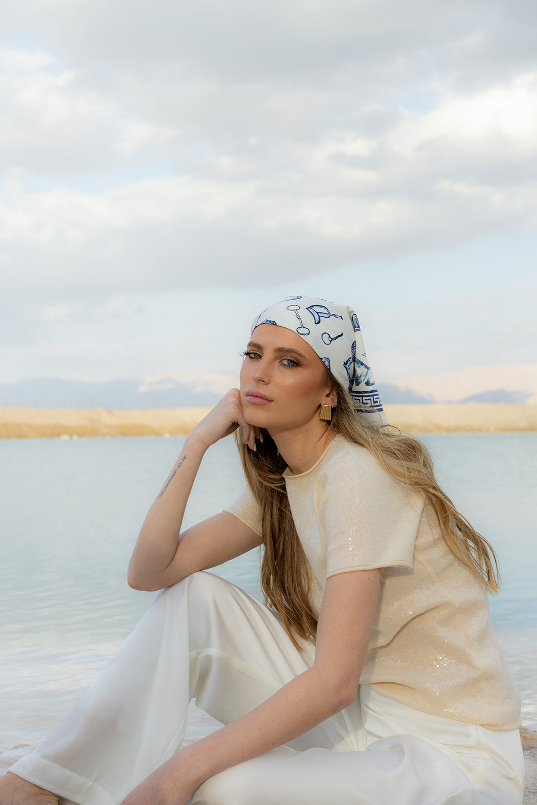 TUK Polo Hour Silk Bandana with refined equestrian print styled as a silk headscarf, paired with a cream outfit by the water.
