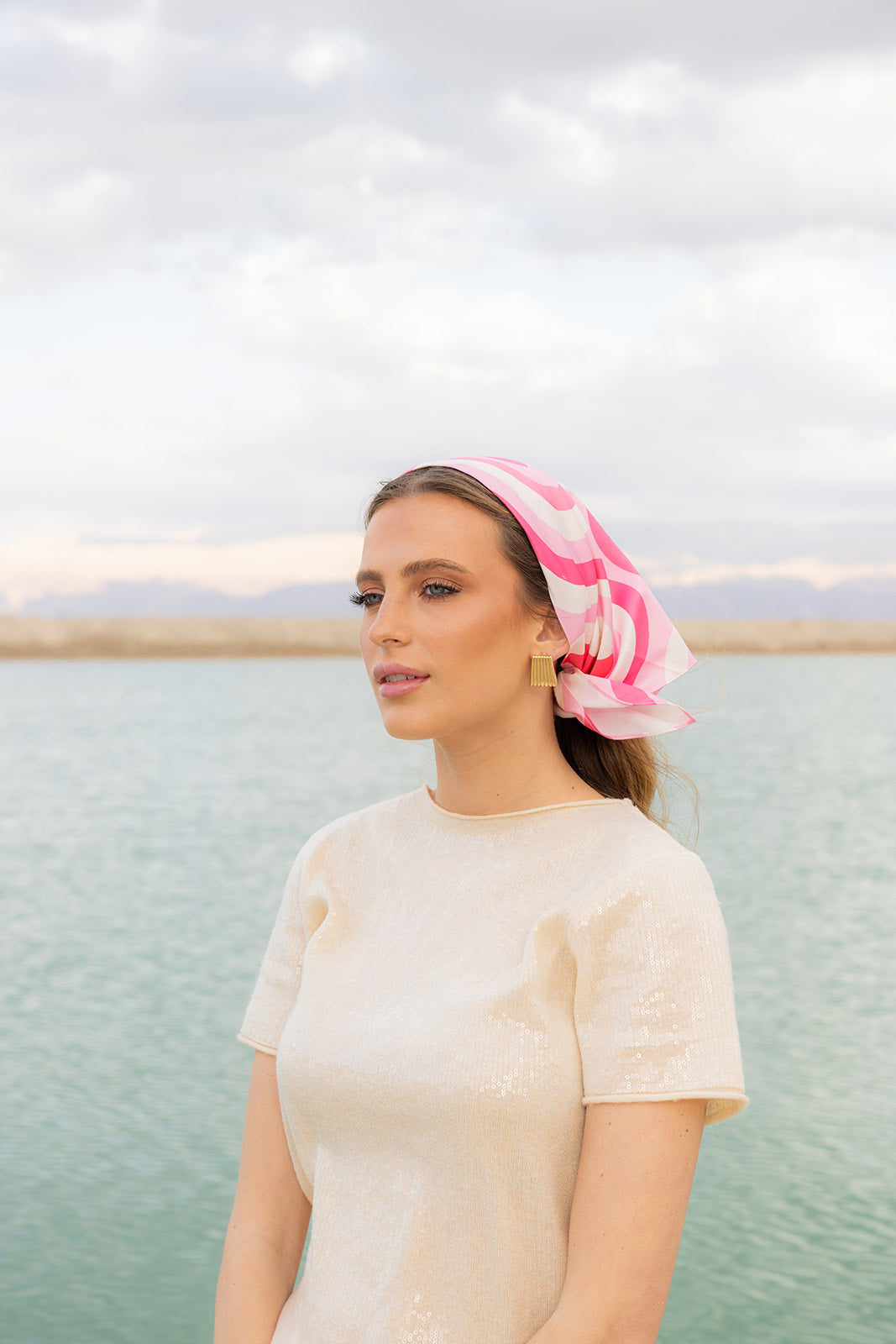 Model wearing TUK Pretty In Motion Silk Bandana in a pink geometric print, styled for a timeless seaside look.