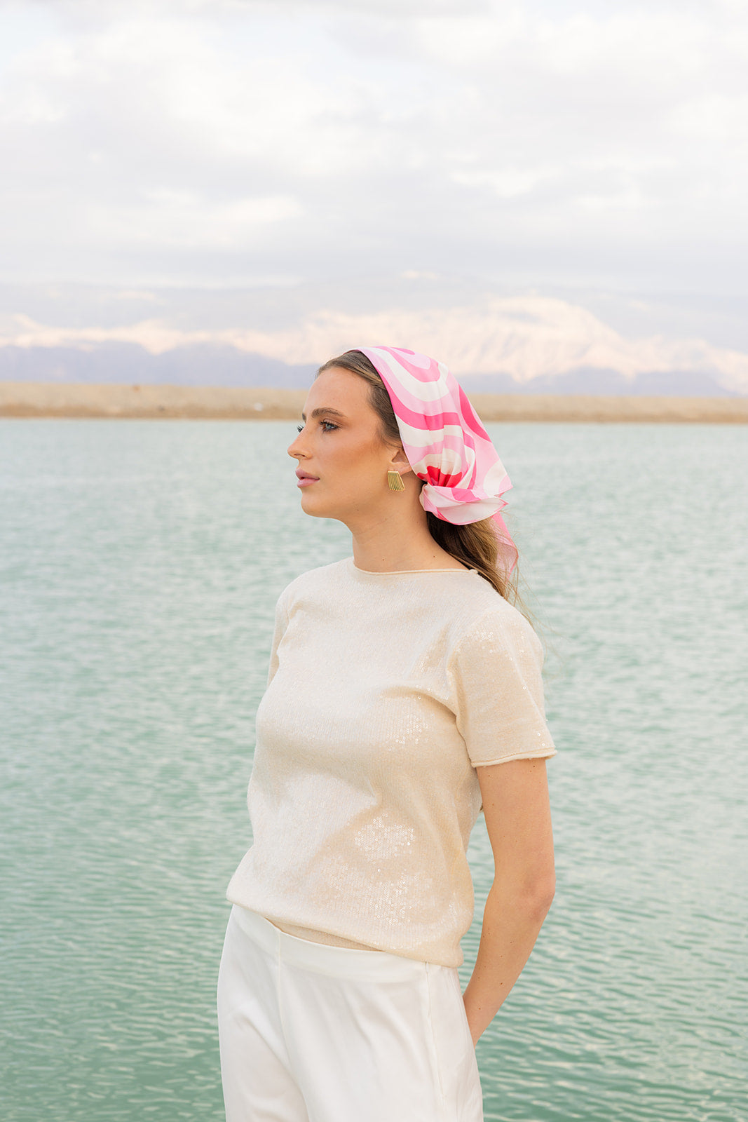 Model wearing TUK Pretty In Motion Silk Bandana in pink geometric print, styled for a chic coastal resort look.