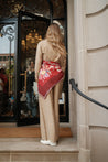 Model wearing TUK’s Redacted Head Scarf styled as a waist wrap, featuring red floral print and soft pink border accents.
