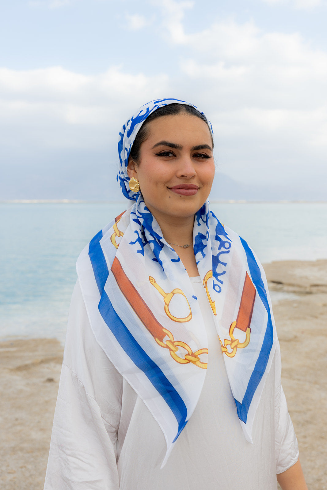Rein It In Head Scarf by Tie Ur Knot featuring a blue equestrian-inspired chain print, styled elegantly by the waterfront.
