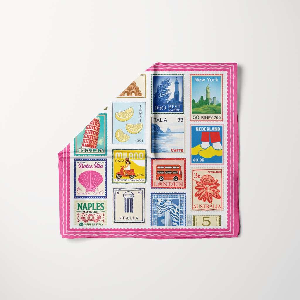 Colorful travel stamp print silk headscarf with pink border, featuring global landmarks, TUK Return To Sender design chic look.