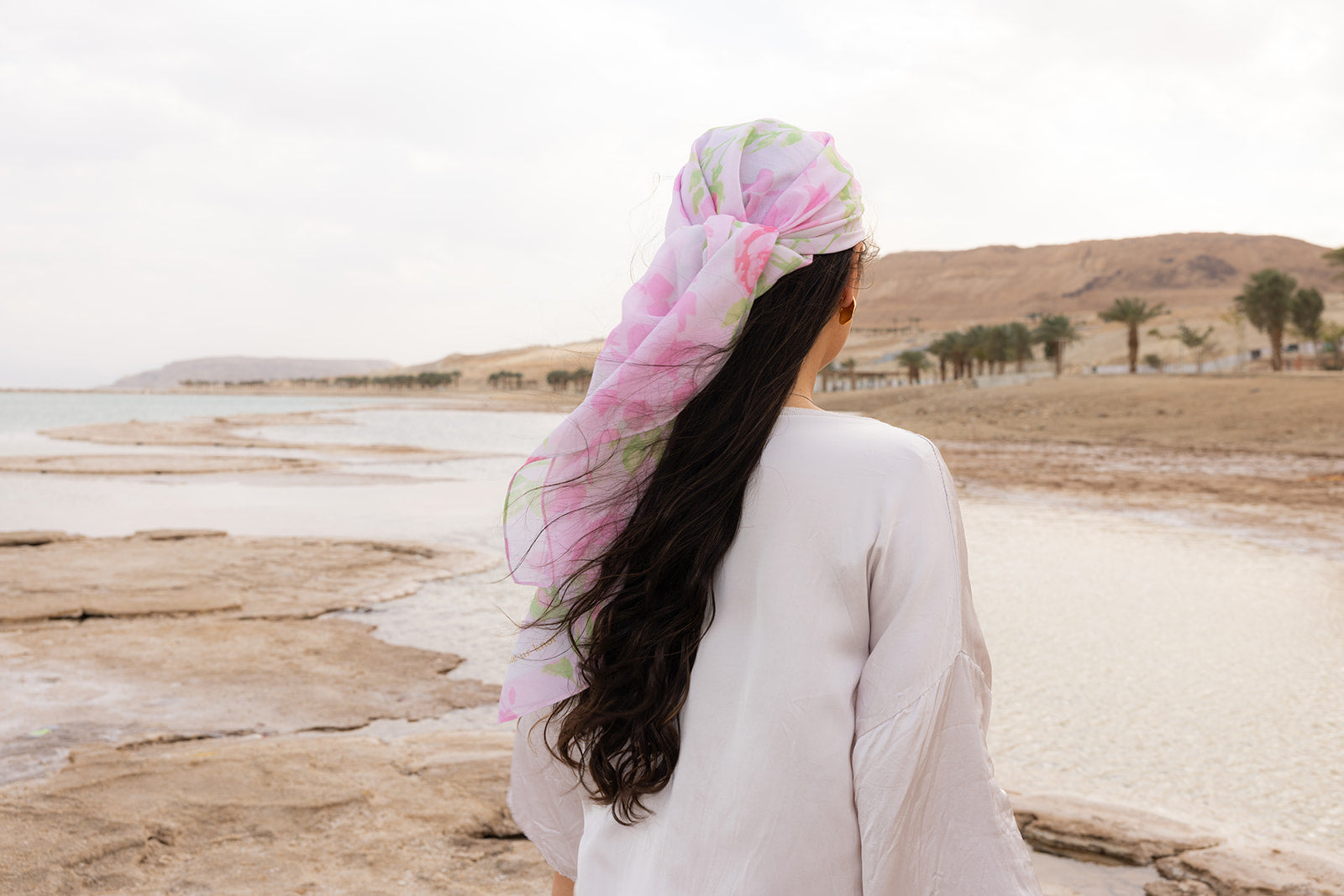 Rose To The Occasion Head Scarf by Tie Ur Knot in a pink floral print, flowing gracefully in a chic coastal desert setting.