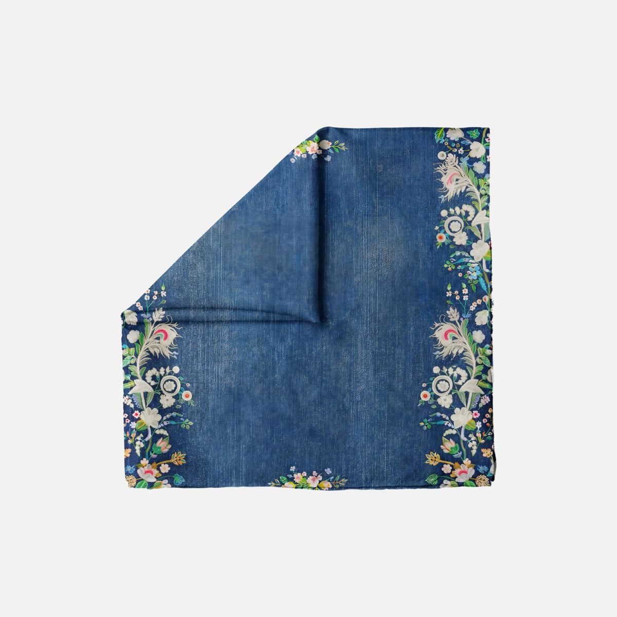 Good Genes Head Scarf, a blue square scarf with a floral and peacock feather border, folded to show its texture