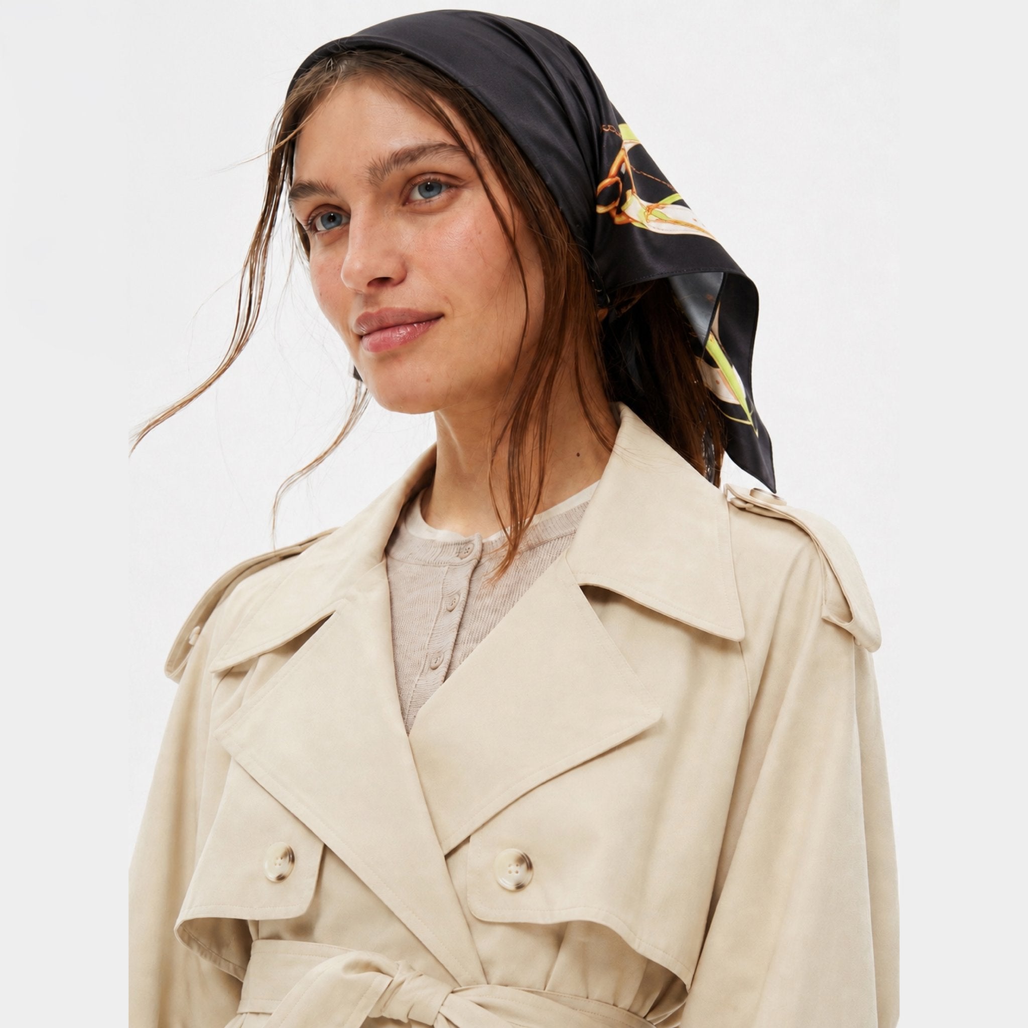 Hold Your Horses Silk Bandana, black, with a pattern of golden snaffle bits, worn on a model's head