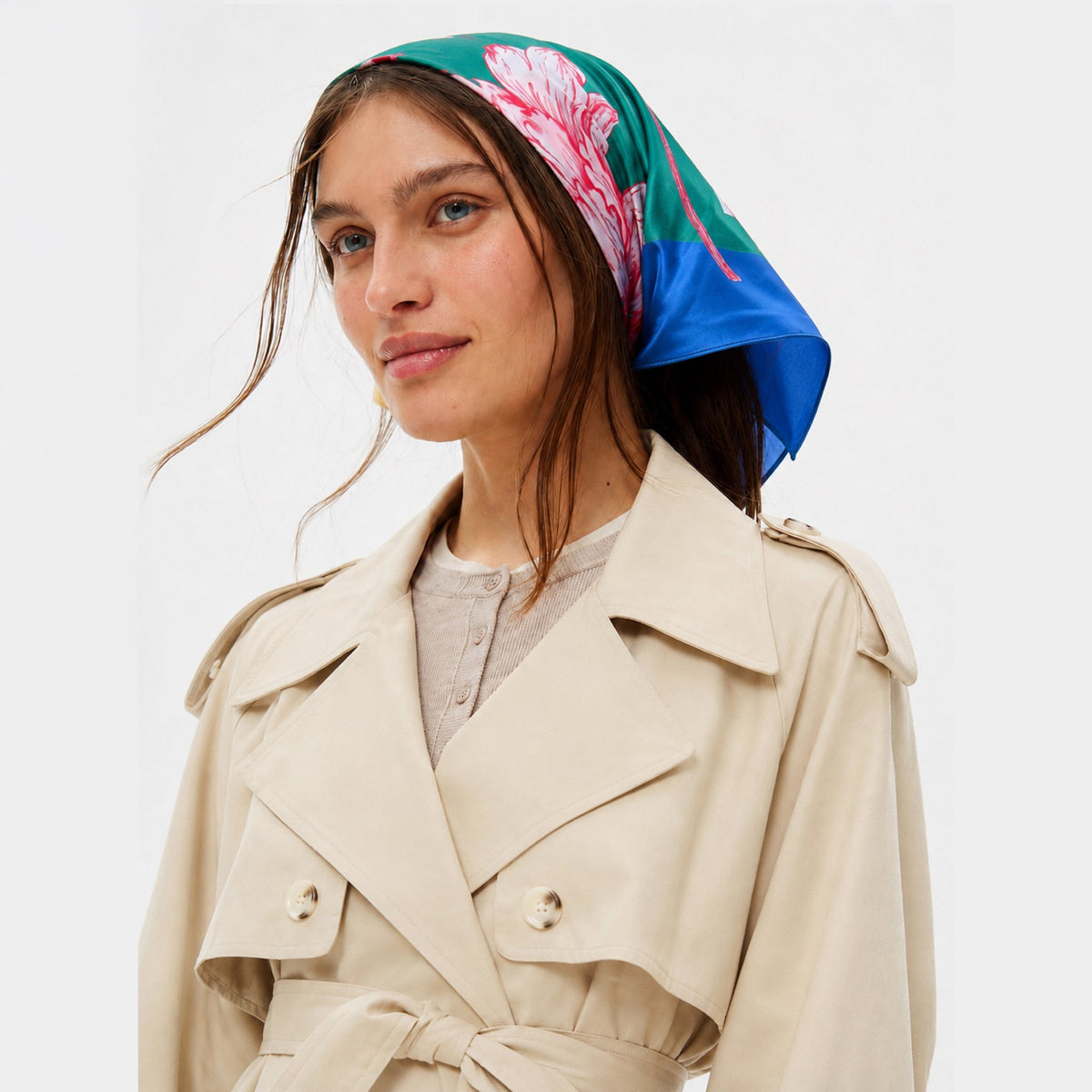 Peony For Your Thoughts Silk Bandana, worn by a woman over her hair. It is green, blue, and pink.
