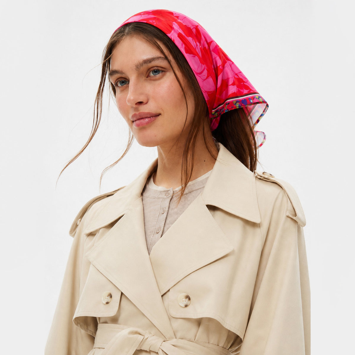 Prima Ballerina Silk Bandana with a floral pattern in shades of red and pink, worn on the head by a person in a beige trench